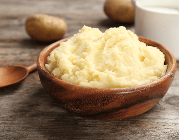 A picture of mashed potatoes in a wooden bowl
