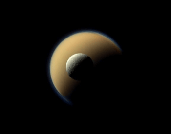 A photo of the Rhea moon in front of the Titan moon.