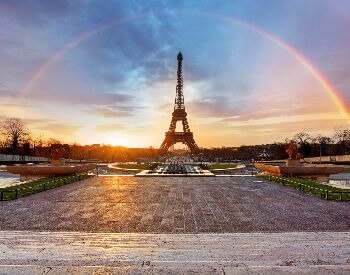 A picture of the Eiffel Tower with a rainbow in the sky above it