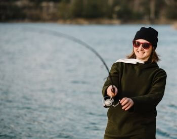 A picture of a woman catching a fish in a lake