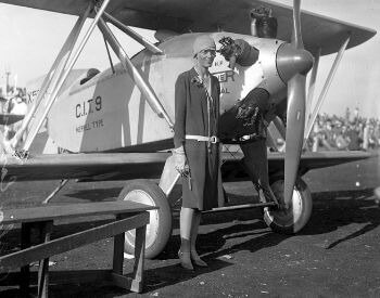 A picture of Amelia Earhart standing next to an airplane