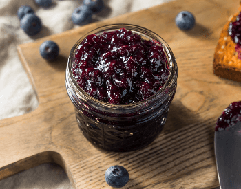 A picture of a glass jar that contains blueberry jam