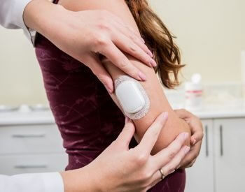 A picture of a woman getting an external blood sugar testing device