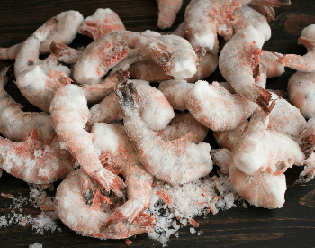A picture of frozen raw shrimp on a table