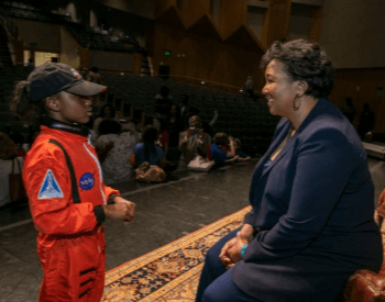 A photo of Mae Jemison speaking with a second grader at an event