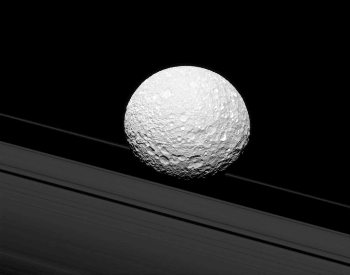 A photo of the moon Mimas near two of Saturn's rings