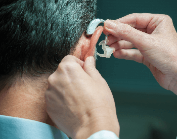 A picture of someone putting on a hearing aid