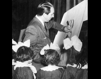 A picture of Walt Disney drawing Goofy for a group of girls